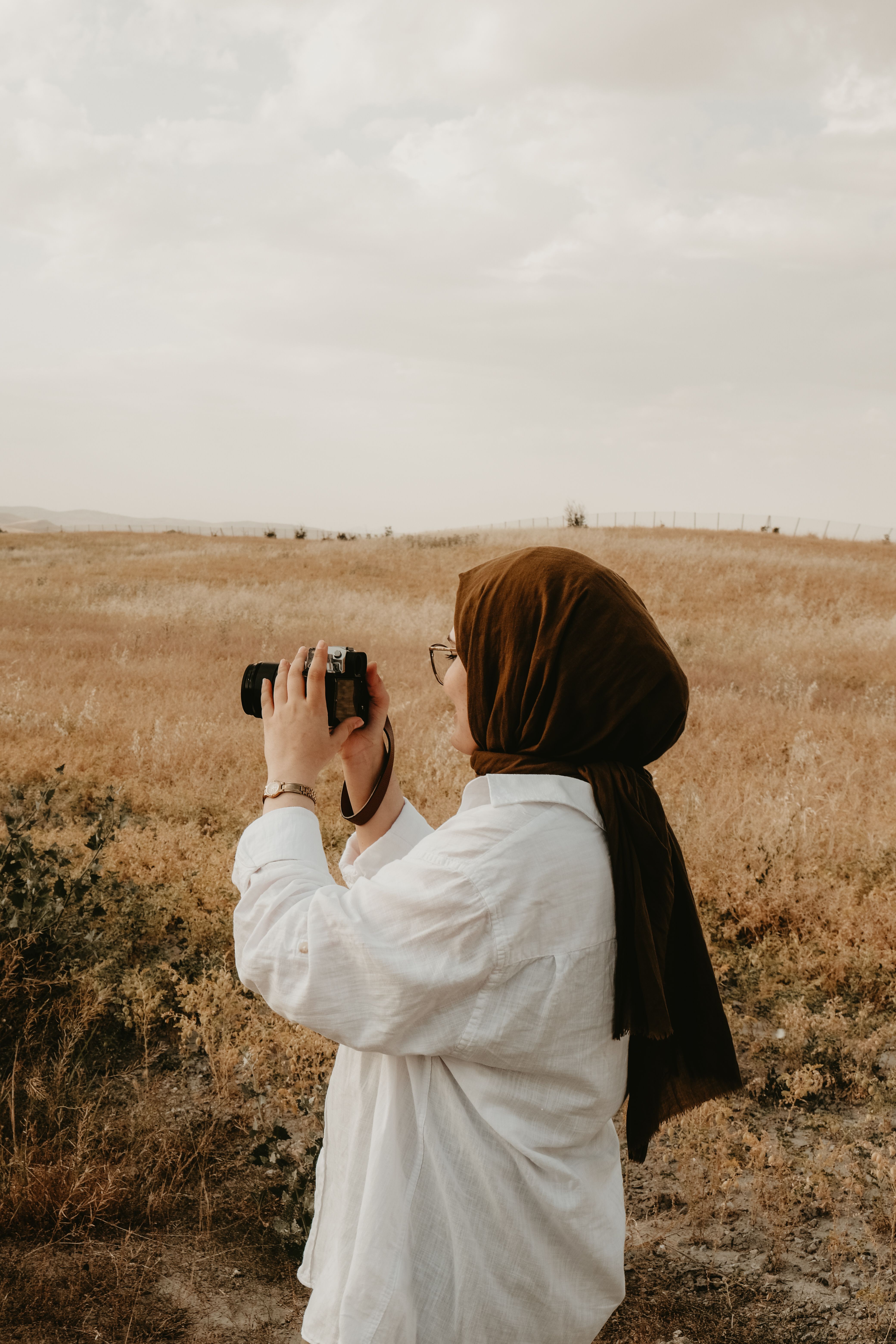 A photographer holding a camera in a golden field