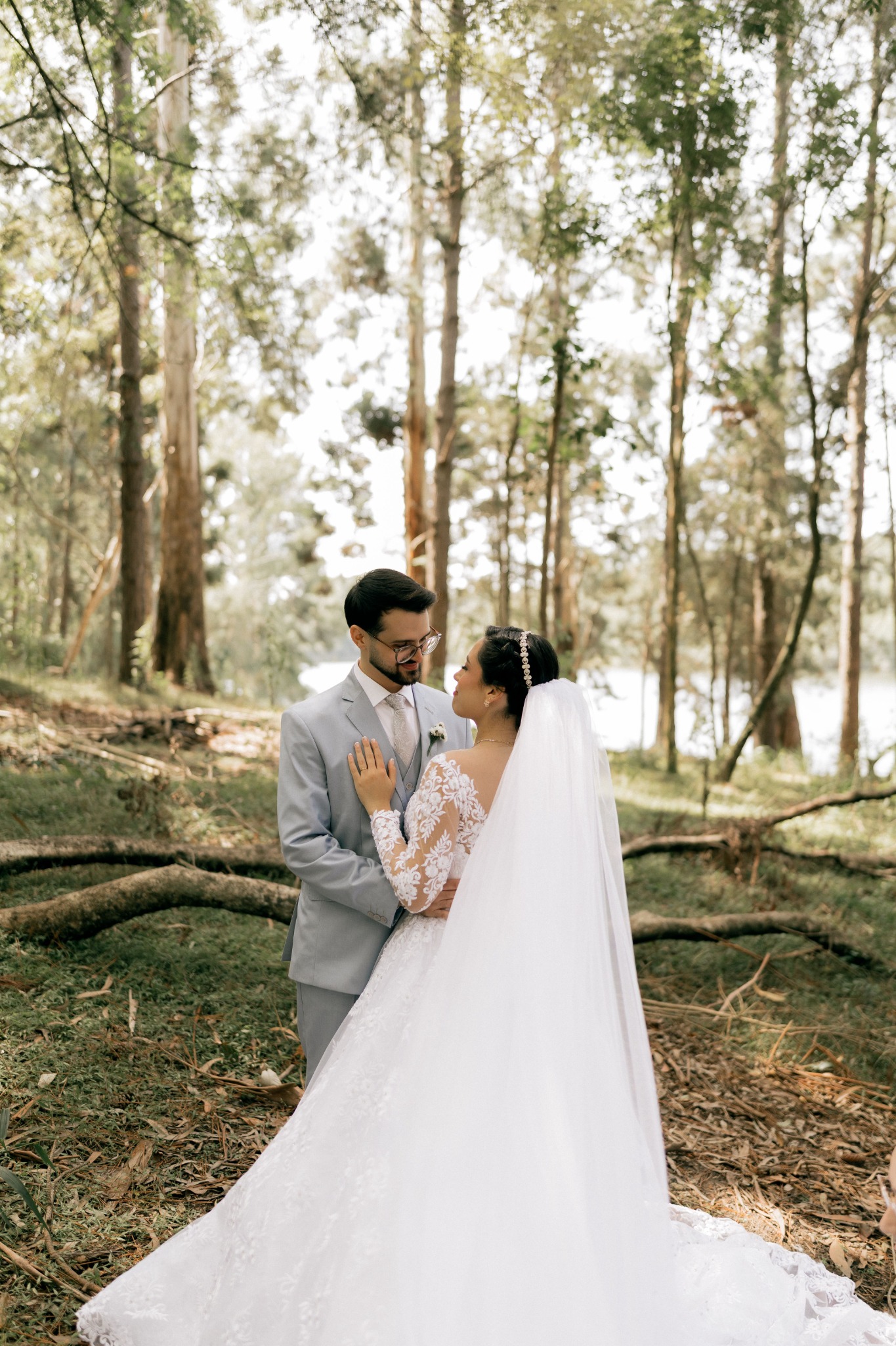 A bride and groom holding each other among sunlit trees