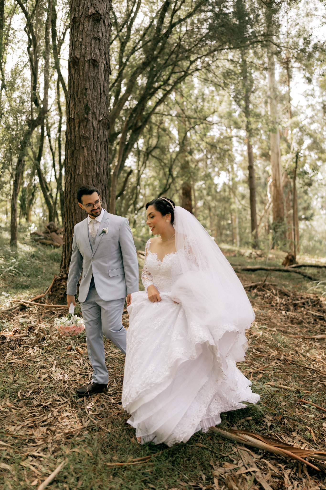 A bride and groom walking together through the woods